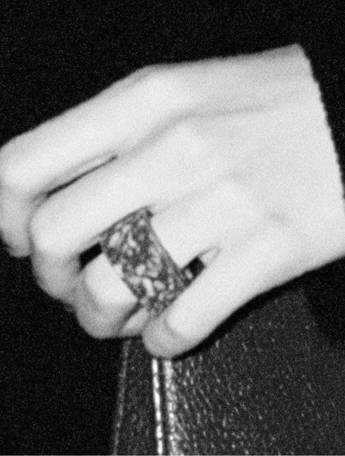 Une main portant une large bague repose sur une banquette de cuir