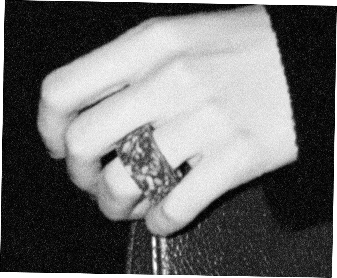 Une main portant une large bague repose sur une banquette de cuir sombre