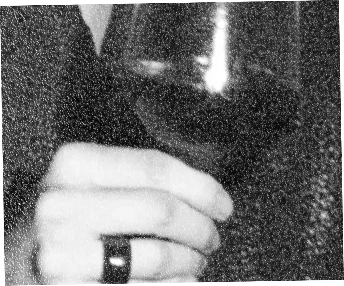 Une main portant une bague tient un verre de vin devant une étoffe sombre