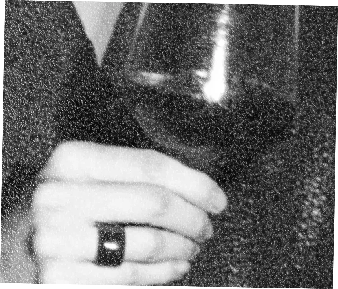 Une main portant une bague tient un verre de vin, grain argentique